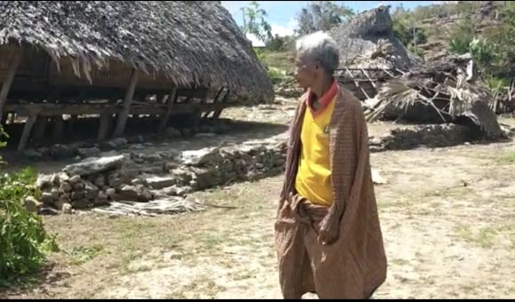 A man in fronVideo still of a man in front of destroyed house in Savu.t of destroyed house in Savu
